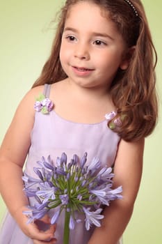 Sweet pretty young girl holding a large agapanthus liily flower.