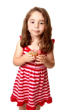 Young child holding a pink iced doughnet.   She is wearing a pink and red striped dress with little pink  heart buttons.