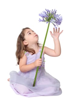 Pretty young little girl sitting plays with a beautiful flower
