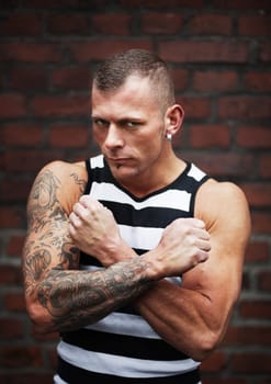 Serious muscular man standing against a brick wall  selective focus