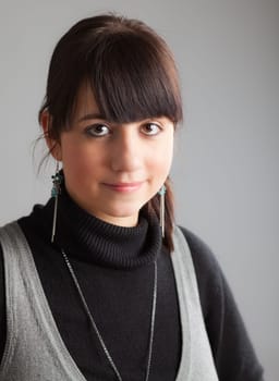 Portrait of a young brunette woman on gray background