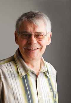 Portrait of a smiling mature man over gray background