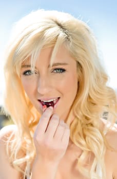 a pretty young woman eating a cherry
