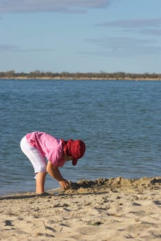 young girl plays in the beach sand on a sunny day