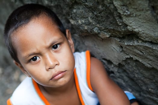 Portrait of a young Philippine boy from poverty-stricken area against wall