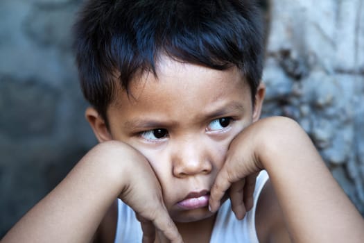 Young Filipino boy portrait against wall - sad expression, poverty