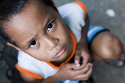 Portrait of a young Asian boy from poverty-stricken area. Natural light, Manila, Philippines.