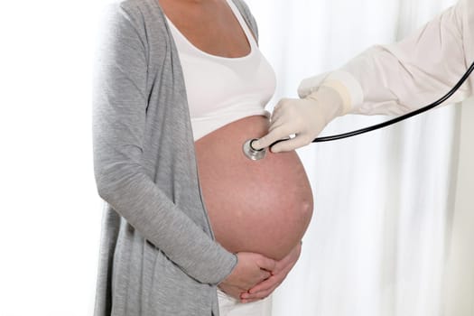 Doctors in the study and listen to the belly of a pregnant woman with stethoscope