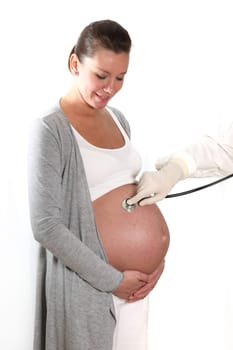 doctor with stethoscope examining the abdomen of a pregnant woman