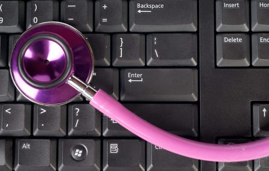 pink stethoscope on a computer keyboard