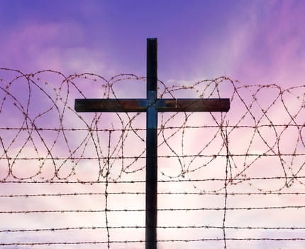 cross of christ behind rolls of barbed wire