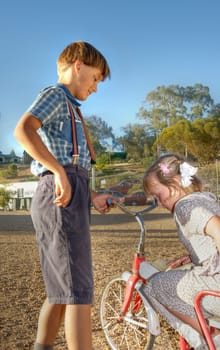 a young gentleman helps a little girl of the old tricycle