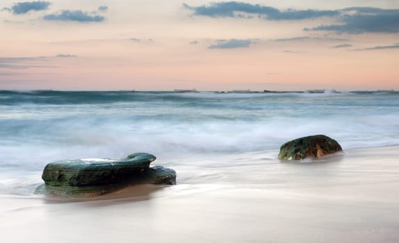 water on rocks on the beach at sunset