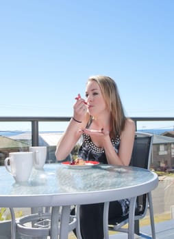 young woman with profiterole dessert in outdoors cafe