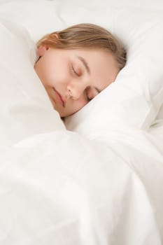 young woman asleep in bed under covers