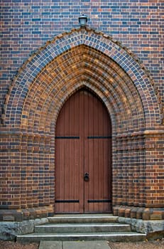 an arched brick doorway with wooden door leading into the church