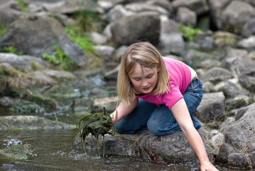 young girl helps clean the weed out of the river