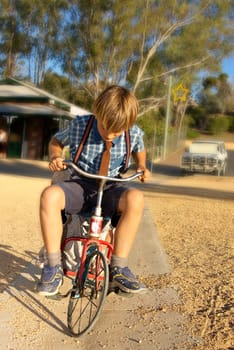 young boy in old style clothing rides a tricycle