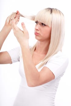 Portrait of beautiful girl touching her weak hair and looking sad