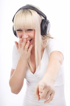 Portrait of laughing woman listening music and pointing down on an isolated white background
