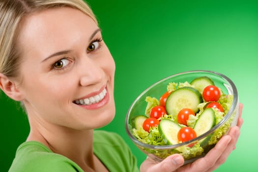 Healthy lifestyle - woman holding vegetable salad on green background