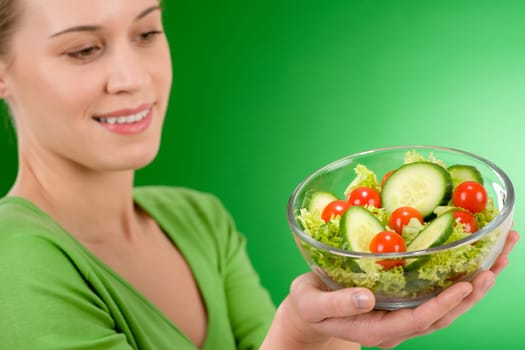 Healthy lifestyle - woman holding vegetable salad on green background