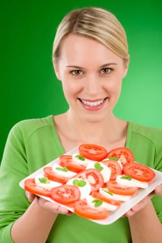 Healthy lifestyle - woman with caprese salad on green background