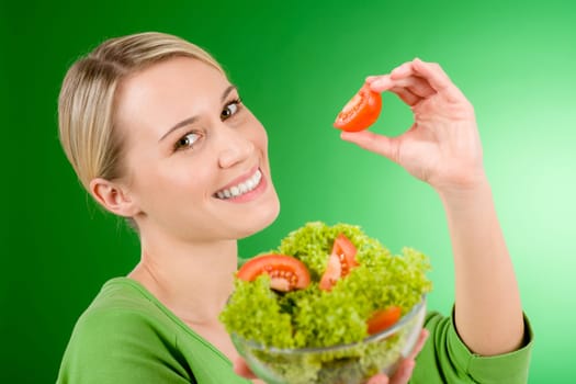 Healthy lifestyle - woman holding vegetable salad on green background