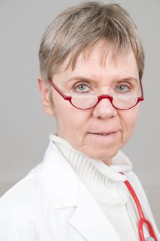 Head and shoulders portrait of an elderly woman in a white coat and red stethoscope around her neck
