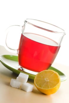 Transparent tea cup with red tea,lemon and sugar