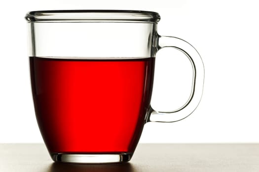 Transparent tea cup with red tea against white background