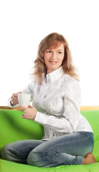 Smiling blond woman on sofa holds a cup of coffee and watches TV