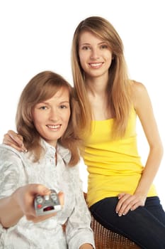 Two smiling pretty blond girls watch TV  isolated on white background