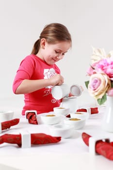 Girl helps to set the table - pouring tea