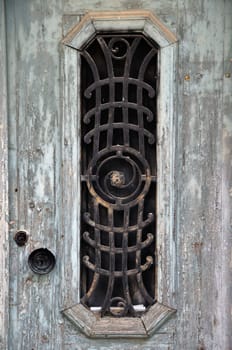 Weathered wooden door with peeling paint and vintage metalwork pattern.