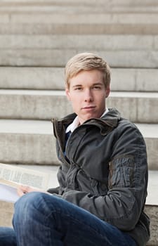 Young blond handsome guy sitting with a book