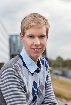 Smiling young handsome blond man standing outdoors