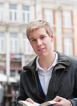 Young handsome man outdoors holding a book in his hands