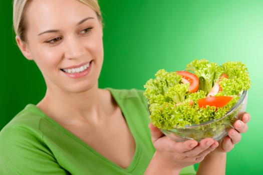 Healthy lifestyle - woman holding vegetable salad on green background