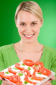 Healthy lifestyle - woman with caprese salad on green background