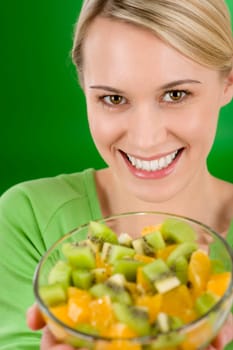 Healthy lifestyle - woman holding fruit salad bowl on green background