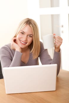 Blond woman with white mug and laptop