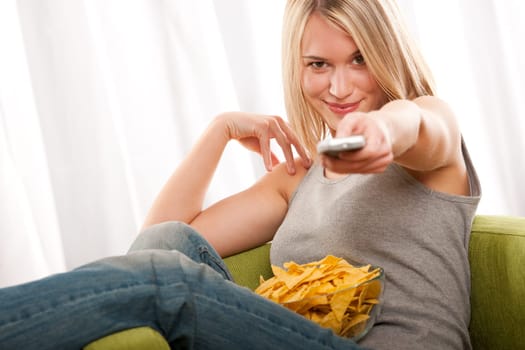 Blond teenage girl sitting on green armchair