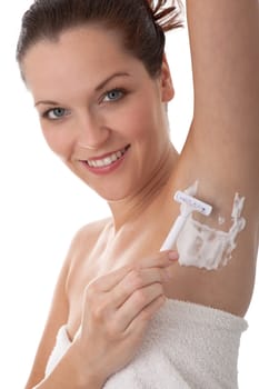 Smiling woman shaving her armpit using white razor