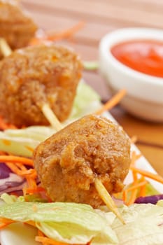 Meatballs skewer, with salad and tomato sauce, on wooden background