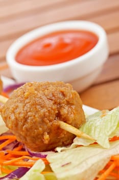 Meatballs skewer, with salad and tomato sauce, on wooden background