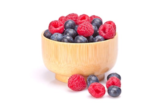 Blueberries and raspberries in a bowl with soft shadow on white background. Shallow depth of field