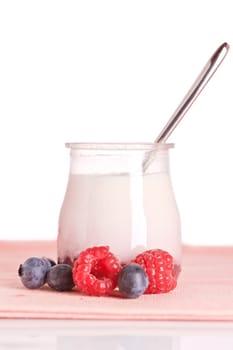 Delicious glass yogurt with a spoon and fresh raspberries and blueberries. Shallow depth of field