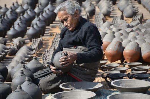 old nepalese woman sitting in pottery and is working