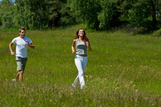 Young couple jogging outdoors in spring nature on sunny day